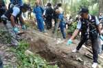 Thai police officials measure a shallow grave in Padang Besar, Songkhla province, southern Thailand, Saturday, May 2, 2015.