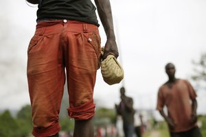 A demonstrators carrying a bag of rocks faces off with riot police in the Musaga district of Bujumbura, Burundi, Monday, May 4, 2015.