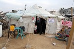 File - A woman leaves her tent near the ruins of her house which witnesses said was destroyed by Israel shelling during a 50-day conflict last summer, east of Khan Younis in the southern Gaza Strip, January 27, 2015.