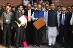 Indian Finance Minister Arun Jaitley, center in blue jacket, display a briefcase containing union budget for the year 2015-16 as he leaves his office for Parliament to present the union budget in New Delhi, India, Saturday, Feb. 28, 2015.