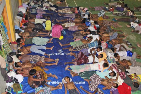 Migrants sleep on the floor at a sports stadium that was turned into a temporary shelter in Lhoksukon, Aceh province, Indonesia, Tuesday, May 12, 2015.