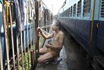 An Indian passenger takes a bath beside rail tracks on a hot summer day at a railway station in Jammu, India, Monday, May 25, 2015.