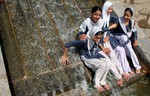 School Girls enjoy on a cascading waterfall in a pond at the Nishat Mughal Garden, which overlooks Dal Lake, in Srinagar on July 04, 2012.