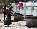 A Rohingya migrant man carries a bucket to prepare take a shower at a temporary shelter in Kuala Langsa, Aceh province, Indonesia, Sunday, May 24, 2015.