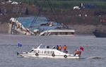 Rescuers on a boat watch the capsized ship is lifted by cranes, on the Yangtze River in Jianli county of southern China’s Hubei province, as seen from across the river from Huarong county of southern China’s Hunan province, Friday, June 5, 2015.