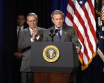 File - Secretary of Defense Donald H. Rumsfeld applauds while President George W. Bush makes remarks at the Pentagon, Washington D.C., 24 November, 2003.