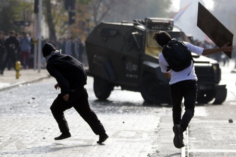 A police vehicle is attacked by protesters during a march demanding more participation in the education reform discussions, in Santiago, Chile, Wednesday, June 10, 2015.