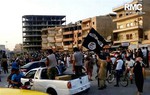 This undated image posted by the Raqqa Media Center, a Syrian opposition group, on Monday, June 30, 2014, which has been verified and is consistent with other AP reporting, shows fighters from the al-Qaida linked Islamic State of Iraq and the Levant (ISIL) during a parade in Raqqa, Syria. Militants from an al-Qaida splinter group held a military parade in their stronghold in northeastern Syria, displaying U.S.-made Humvees, heavy machine guns, and missiles captured from the Iraqi army for the first time since taking over large parts of the Iraq-Syria border.