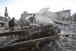 File - In this Nov. 19, 2014 photo, Kurdish fighters show the extent of the damage from a truck bomb in Kobani, Syria.