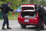 An officer with the New York State Department of Corrections draws his gun as his partner opens the trunk of a vehicle inspection at a roadblock near the Clinton Correctional Facility, Tuesday, June 16, 2015 in Dannemora, N.Y.