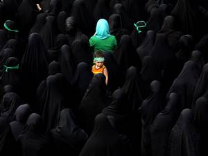 25 June 2015: A child looks on as Iranian mourners attend the funeral of Mohammad Hamidi, Hasan Ghafari and Ali Amrai, all three members of the Islamic Republic's Revolutionary Guards reportedly killed in Syria, in Tehran