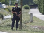 A police officer guards the road leading to a plant where an attack took place in Saint-Quentin-Fallavier, southeast of Lyon, France, Friday, June 26, 2015.