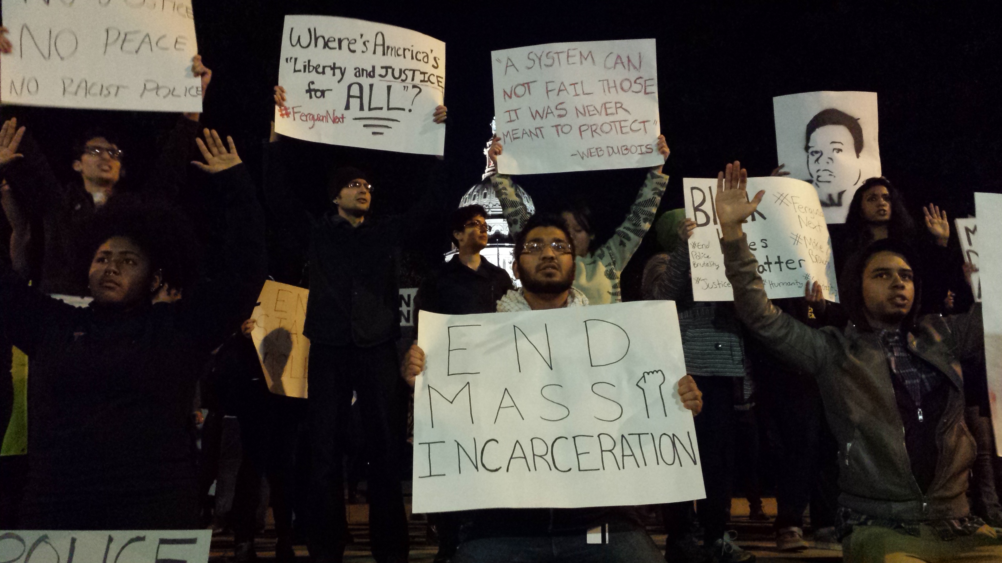 Demonstrators raise hands outside of Texas Capitol, indicating innocence of Mike Brown