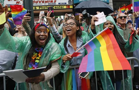 Spectators wave rainbow-colored gay pride flags during the Heritage Pride March in New York, Sunday, June 28, 2015.