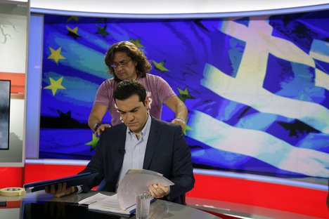 Greece's Prime Minister Alexis Tsipras takes a look at his notes as a technician prepares him before a TV interview at the State Television (ERT) in Athens, Monday, June 29, 2015.