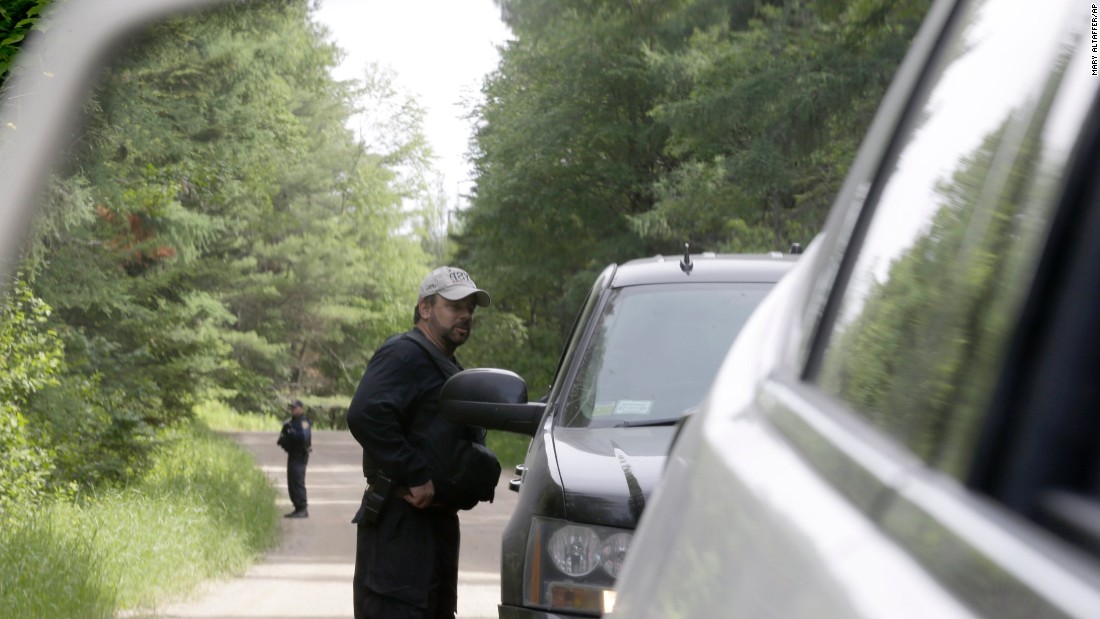 Law enforcement officials are seen in the side-view mirror of a car as they stand guard June 28 in Duane, New York.