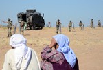 File - Turkish soldiers stand guard as people from the Syrian town of Ayn al-Arab or Kobani, in the background, wait to cross into Turkey following the attacks by IS militants as seen from the Turkish side of the border in Suruc, Turkey, Friday, June 26, 2015.