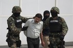 File - Joaquin "El Chapo" Guzman is escorted to a helicopter in handcuffs by Mexican navy marines at a navy hanger in Mexico City, Mexico, Saturday, Feb. 22, 2014.