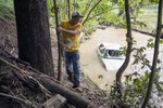 Ralph Whitaker checks a partially submerged vehicle while searching for his brother who was missing after deadly flooding in Flat Gap, Ky., Tuesday, July 14, 2015.