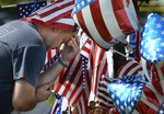 Chris Hollingsworth prays by a makeshift memorial outside the Armed Forces Career Center Saturday, July 18, 2015, in Chattanooga, Tenn. The U.S. Navy says a sailor who was shot in the attack on a military facility in Chattanooga has died, raising the death toll to five people.