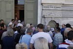 The first customers, most of them pensioners, stand in a queue to enter a branch at National Bank of Greece headquarters in Athens, Monday, July 20, 2015.