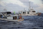 File: Japanese Coast Guard vessel, right, sails alongside Japanese activists' fishing boat, left, near a group of disputed islands called Diaoyu by China and Senkaku by Japan, early Sunday, Aug. 18, 2013.