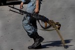 An Afghan police officer walks near the site of a suicide attack outside the British Council in Kabul, Afghanistan, Friday, Aug. 19, 2011.