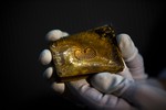 A worker of the ministry holds up for photographers a gold tobacco box from the shipwreck of a 1804 galleon, on its first display to the media at a Ministry building, in Madrid, Friday, Nov. 30, 2012.