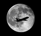 A United Airlines passenger plane crosses the waning gibbous moon, one day after a full moon, late Thursday, July 2, 2015, in in Whittier, Calif. There will be two full moons in July, the next one known as a blue moon, will be on July 31.