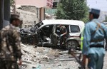 In this Tuesday, July 7, 2015 file photo, Afghan security personnel inspect a damaged vehicle at the site of a suicide attack that targeted a NATO convoy in Kabul, Afghanistan.