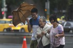 An elderly woman is escorted in the strong winds from Typhoon Soudelor in Taipei, Taiwan, Friday, Aug. 7, 2015.