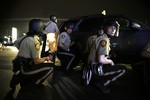 Police take cover behind a vehicle during a protest in Ferguson, Mo., Sunday, Aug. 9, 2015.