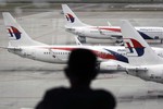 A man views a fleet of Malaysia Airlines plane taxied on the tarmac of the Kuala Lumpur International Airport, Malaysia, Thursday, Jan. 29,  2015. Malaysia's Civil Aviation Authority has officially declared the MH370 crash an accident, fulfilling a legal obligation that will allow efforts to proceed with compensation claims. (AP Photo/Joshua Paul)