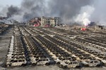 Smoke billows out from the site of an explosion that reduced a parking lot filled with new cars to charred remains at a warehouse in northeastern China's Tianjin municipality, Thursday, Aug. 13, 2015.