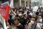 Residents, some wearing masks hold banners and placards as they stage a protest outside a hotel where officials held daily media conferences in northeastern China's Tianjin municipality Monday, Aug. 17, 2015. About a hundred people whose residences were damaged in the massive Tianjin blasts gathered Monday for a protest to demand compensation from the government.