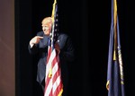 Republican presidential candidate businessman Donald Trump points to the American flag as he takes the stage to speak to a campaign town hall Wednesday, Aug. 19, 2015, at Pinkerton Academy in Derry, N.H.