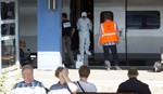 People wait for a train in the foreground as members of a police forensics team take part in an investigation next to a Thalys train on the platform at Arras train station, northern France, Saturday, Aug. 22, 2015.