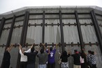 File - In this July 14, 2013 photo, pastors and others raise their arms on the San Diego side of a border fence during a cross-border Sunday religious service with others on the Tijuana, Mexico side of the fence.