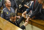 In this Tuesday, Oct. 21, 2014 file photo Oscar Pistorius, center, greets family members, right, as he is led down to the cells of the court in Pretoria, South Africa to serve a five year prison sentence for culpable homicide for the killing of his girlfriend Reeva Steenkamp in 2013.