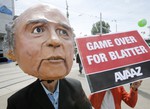 A protester wearing a mask depicting FIFA President Sepp Blatter stands in front of the building where the 65th FIFA congress takes place in Zurich, Switzerland, Friday, May 29, 2015.