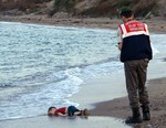 In this Sept. 2, 2015 file photo, a paramilitary police officer investigates the scene before carrying the lifeless body of Aylan Kurdi, 3, after a number of migrants died and others were reported missing when boats carrying them to the Greek island of Kos capsized near the Turkish resort of Bodrum.