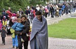 Migrants walk from the main station in Dortmund, Germany, to a hall where they get first attendance Sunday, Sept. 6, 2015.