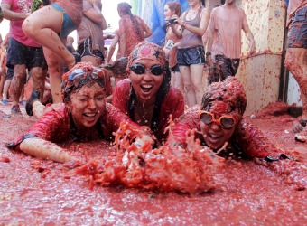 Revelers play in tomato pulp after the annual "Tomatina" (tomato fight) in Bunol, near Valencia, Spain, August 26, 2015. Tens of thousands of festival-goers hurled 170 tonnes of over-ripe tomatoes at each other on Wednesday to celebrate the 70th anniversary of the massive food fight in the small village of Bunol in eastern Spain. REUTERS/Heino Kalis