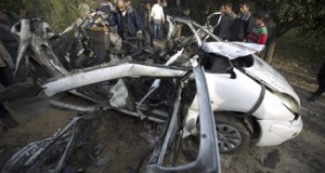 Palestinians gather next to a destroyed car after it was hit by an Israeli air strike in Beit Hanoun. Photograph: Mohammed Abed/AFP/Getty Images