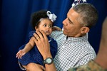 File - President Barack Obama holds a young girl while meeting with Marine personnel and their families at Marine Corps Base Hawaii on Christmas Day, Dec. 25, 2014.