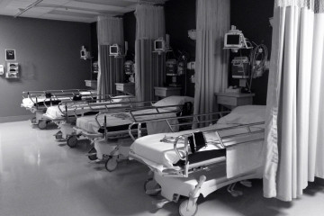 File: Four hospital beds in a row, each with curtains so they can be partitioned for privacy. (Flickr / StudioTempura)