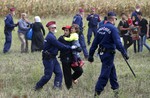 Hungarian police officers stop a group of migrants near a temporary holding center for asylum seekers in Roszke, southern Hungary, Tuesday, Sept. 8, 2015.