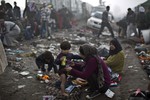 A Syrian woman changes her son's clothes near a makeshift camp for asylum seekers, after crossing the Serbian-Hungarian border near Roszke, southern Hungary, Saturday, Sept. 12, 2015.