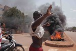 A Burkina Faso protestor gestures in front of burning tires as he and others take to the streets in the city of Ouagadougou, Burkina Faso, Thursday, Sept. 17, 2015. While gunfire rang out in the streets, Burkina Faso’s military took to the airwaves Thursday to declare it now controls the West African country.