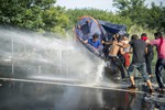 Hungarian police use water canons at the border crossing into Hungary, near Horgos, Serbia, Wednesday, Sept.16, 2015.